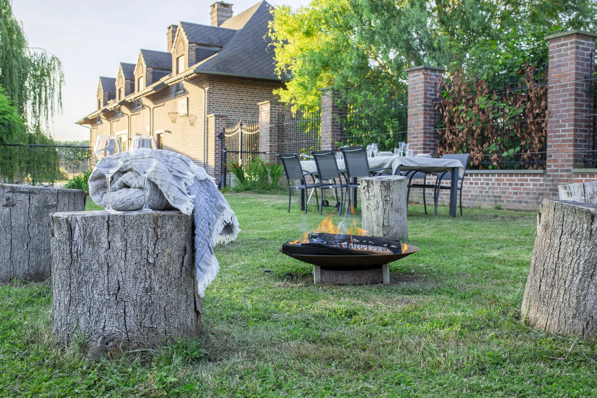 Jardin du gîte avec braséro, table dressée et façade en briques